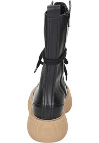 Botte de combat en cuir noir avec une semelle en caoutchouc beige texturée, à lacets à l'avant et fermeture éclair sur le côté. Présente un tige haute et des détails de couture.