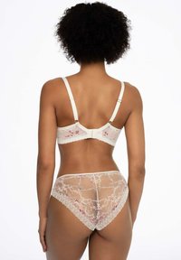 Koronkowy zestaw bielizny w kolorze kości słoniowej z kwiatowym haftem; miękkie miseczki i regulowane ramiączka w staniku, pasujące przezroczyste majtki z falbaniastymi krawędziami.