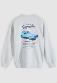 Ανοιχτό γκρι φούτερ με εικονογράφηση ενός μπλε vintage αυτοκινήτου με την ετικέτα "Denim Gremlin" και περιγραφικό κείμενο από κάτω στην πλάτη.