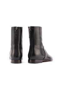 Stivali alla caviglia in pelle nera con zip laterali, finitura liscia, punta arrotondata e tacco in legno basso. Design elegante e minimale.