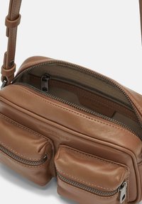 Borsa a tracolla in pelle marrone con una texture liscia; presenta due tasche frontali con zip e un compartimento principale con chiusura a zip.