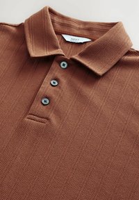 Smeđi pamučni polo majica s reljefnim uzorkom, tri tamne gumbe i oznaku koja prikazuje "NEXT REGULAR FIT."