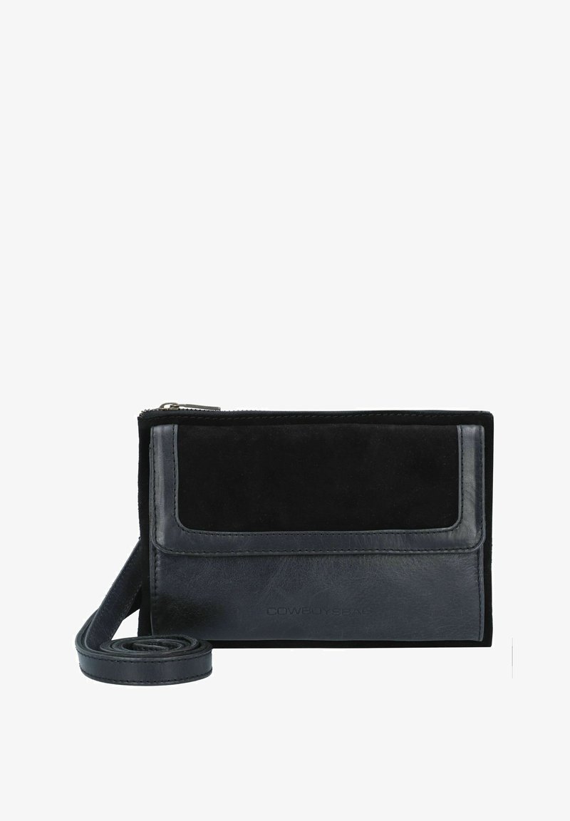 Sac en bandoulière en cuir noir et daim avec fermeture à glissière, rabat avant et une sangle amovible. Présente une texture lisse et un détail de logo.