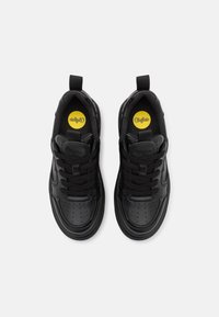 Svarte lær sneakers med rund tå, perforert design og flate lisser. Har en gul logo på innersålen og en løfretning på hælen.