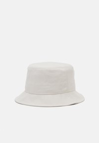 Light beige bucket hat made of soft, textured fabric with a cylindrical crown and wide, downward-sloping brim.