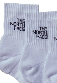Calcetines de crew blancos con textura acanalada, que presentan el logo "THE NORTH FACE" en negro de punto en los laterales. Se muestran dos pares.