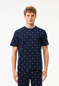 Korte mouwen marineblauwe t-shirt van katoen, met kleine witte alligatorspatronen, ronde hals en een reguliere pasvorm.