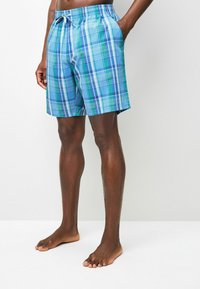 Blaue karierte Badeshorts verfügen über einen bequemen elastischen Bund, einen Kordelzug und Seitentaschen. Das Material scheint leicht und atmungsaktiv zu sein.