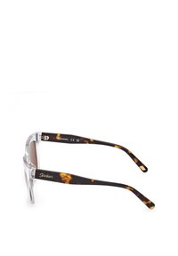 Aurinkolasit, joissa on kirkas etuosa ja ruskeasävyiset linssit. Tempuissa on tumman kilpikonnakuvio ja kultainen logoviba.