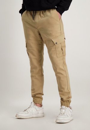 Khaki cargobroek met elastische manchetten, meerdere zakken met drukknoopsluiting en een trekkoord in de taille. Glad materiaal met een relaxte pasvorm.