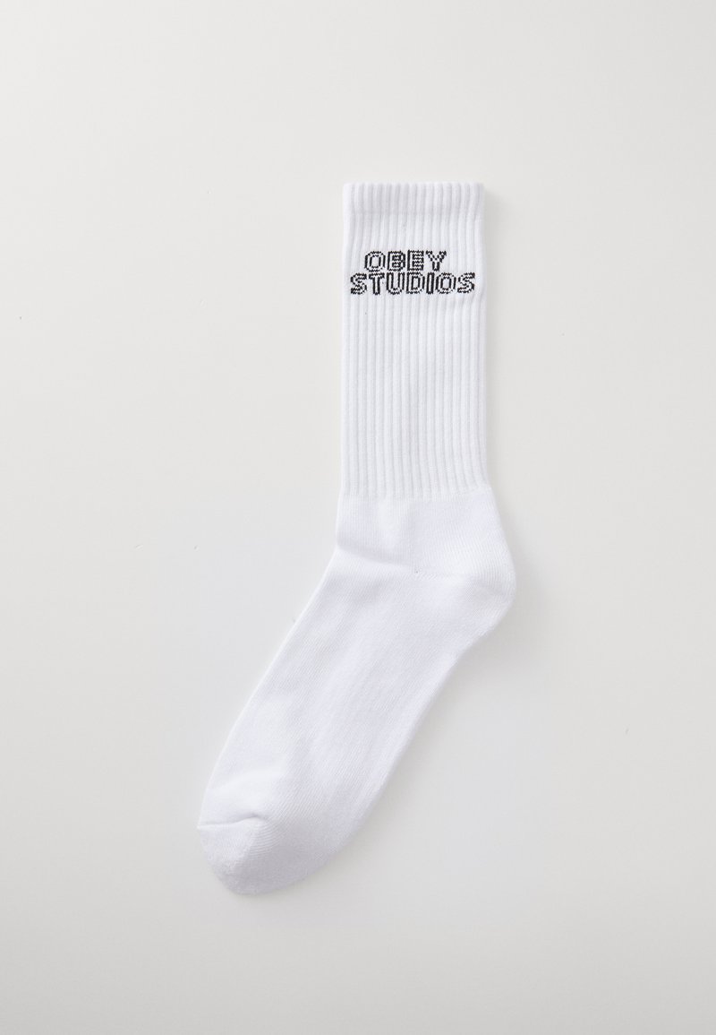 Fehér pamut zokni bordás szegéllyel, fekete "OBEY STUDIOS" felirattal a felső részen. Simaszerkezet, standard sportos forma.