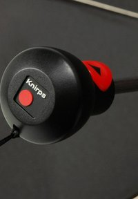 Black and red retractable umbrella handle with a circular, textured grip, featuring a prominent red button and the brand name "Knirps" displayed.