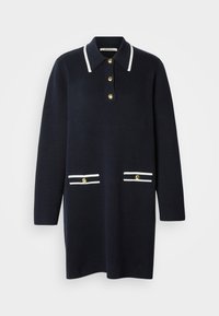 Tengerészkék kötött ruha gallérral, fehér díszítésekkel, három arany gombbal, valamint két elülső zsebbel, fehér csíkokkal és arany gombokkal.