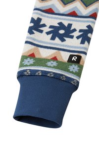 Manga de malha com um padrão de floco de neve multicolorido e montanha em creme, verde, vermelho e azul. Punho canelado em azul-marinho com etiqueta de logo.