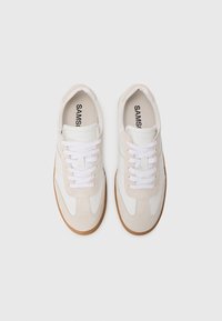 Sneakers bianchi e beige con tomaia in suede e pelle, dotati di lacci bianchi, punta arrotondata e suola in gomma.