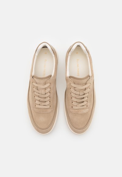 Beige suede sneakers with a rounded toe, laced design, and white rubber soles. Soft texture with minimal branding on the insole.