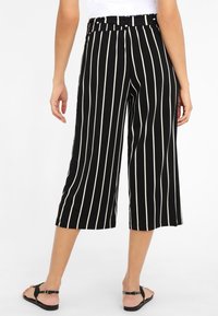 Culottes rayés noir et blanc en tissu doux avec une taille élastique, présentant une longueur courte et une coupe ample.