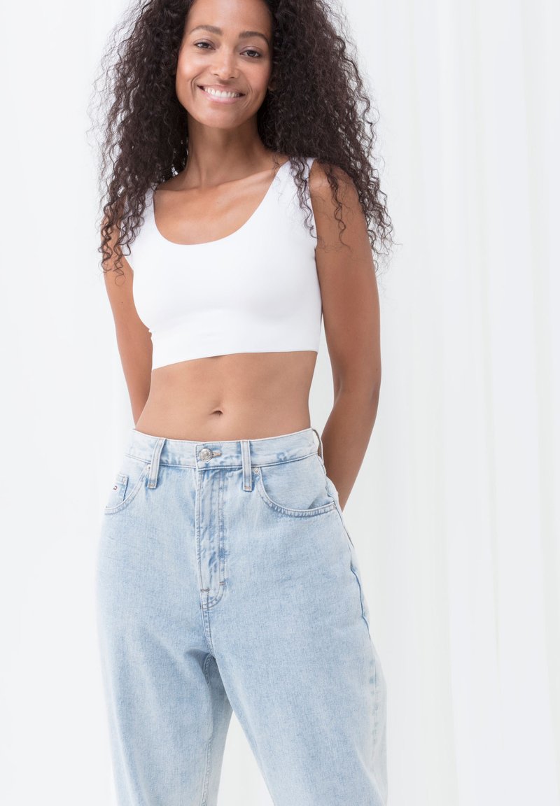 Hvid cropped tanktop med brede stropper parret med højtaljede lyseblå denimjeans; glat stof og afslappet pasform. 