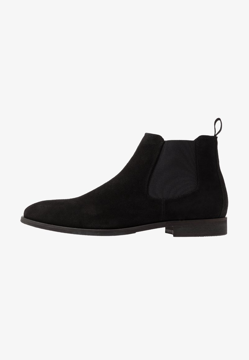 Bottine Chelsea en daim noir avec panneau latéral élastique, languette au talon et petit talon empilé.