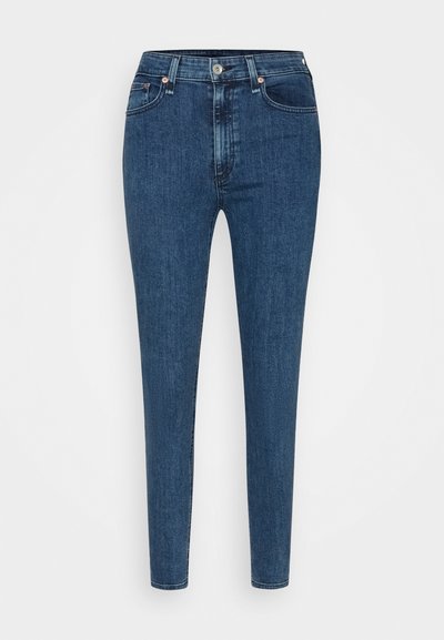 Jeans skinny em denim azul escuro. Apresenta uma cintura alta, bolsos frontais e um fecho com botão na frente. Textura suave com costuras mínimas.