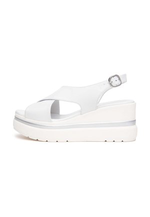 Sandalo con zeppa bianca con suola spessa, punta aperta, cinturini incrociati e fibbia regolabile alla caviglia.