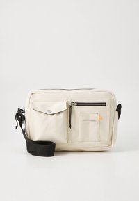 Bézs vászontáska elülső fedélzsebbel, cipzáras rekesszel és egy kis oldalzsebbel. Állítható fekete pánt dombornyomott szöveggel.