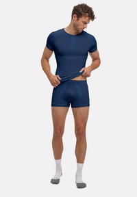 Maillot de compression athlétique bleu marine et short assorti, fabriqués en tissu élastique, avec une construction sans coutures et une coupe ajustée.