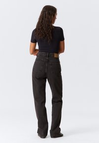 Zwarte high-waisted jeans met een rechte pasvorm, vijf zakken en een tanleren label op de achterkant van de tailleband. Gestructureerde denimstof.