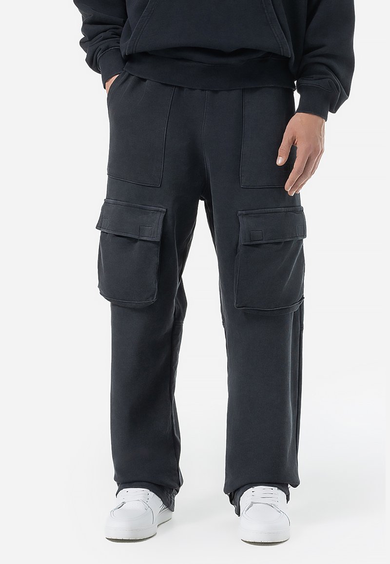 Cargo bukser i mørkegrå stof, med store lommer, en afslappet pasform og en glat overflade. Samlet med hvide sneakers.
