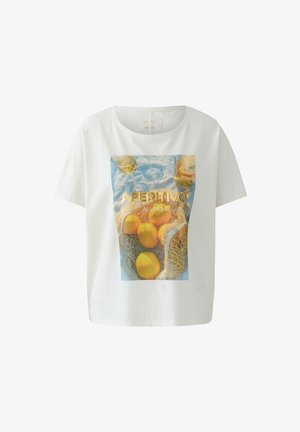 Weißes T-Shirt mit einem Druck von Zitronen in einem Netzbeutel, zwei Weingläsern, einer Flasche und dem Text "APERITIVO AL LIMONE" auf blauem Stoffhintergrund.