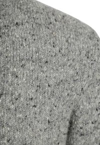Gray knit sweater fabric featuring a textured, speckled pattern with small flecks of white and darker colors throughout.
