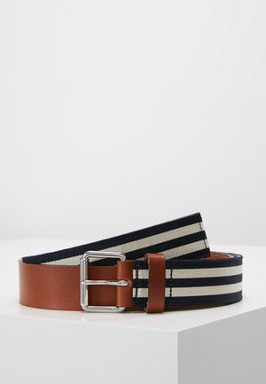 Brunt læderbælte med sølvspænde fastgjort til en navyblå og hvid stribet stofrem, vist sammenrullet på en hvid overflade.