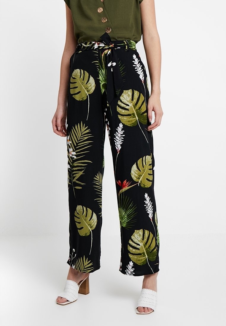 Svarta, vida byxor med ett tropiskt bladdesign i grönt och vitt. Tyget är lätt och har en knytning i midjan.