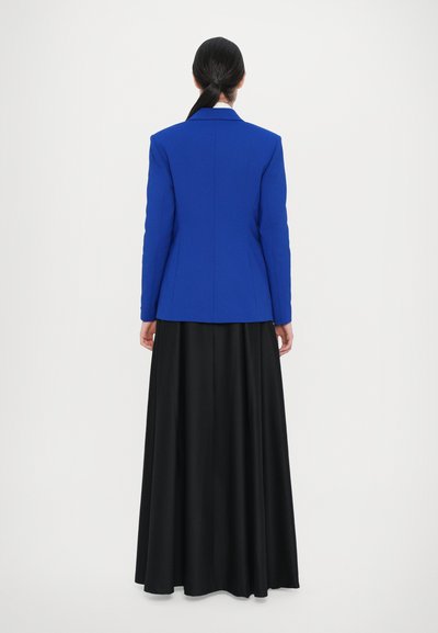 Blue tailored blazer with a structured design, paired with a flowing black maxi skirt. Smooth fabric, long sleeves, and notch lapel details.