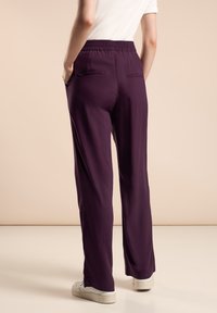 Pantalons légers violets foncés avec une taille élastique, dotés de deux poches arrière et d'une coupe large. Texture lisse.