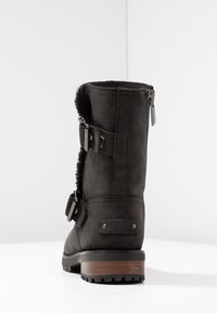 Černé nubukové kotníkové boty s koženým podšívkou, s dvěma sponami, zipem a dřevěným podpatkem. Gumová podrážka pro lepší záběr. Detail s logem UGG.