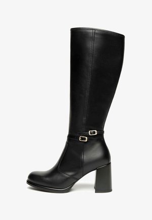 Bottes noires jusqu'au genou en cuir lisse, avec un talon épais, une sangle à la cheville ornée de petites boucles en or, et un design épuré.