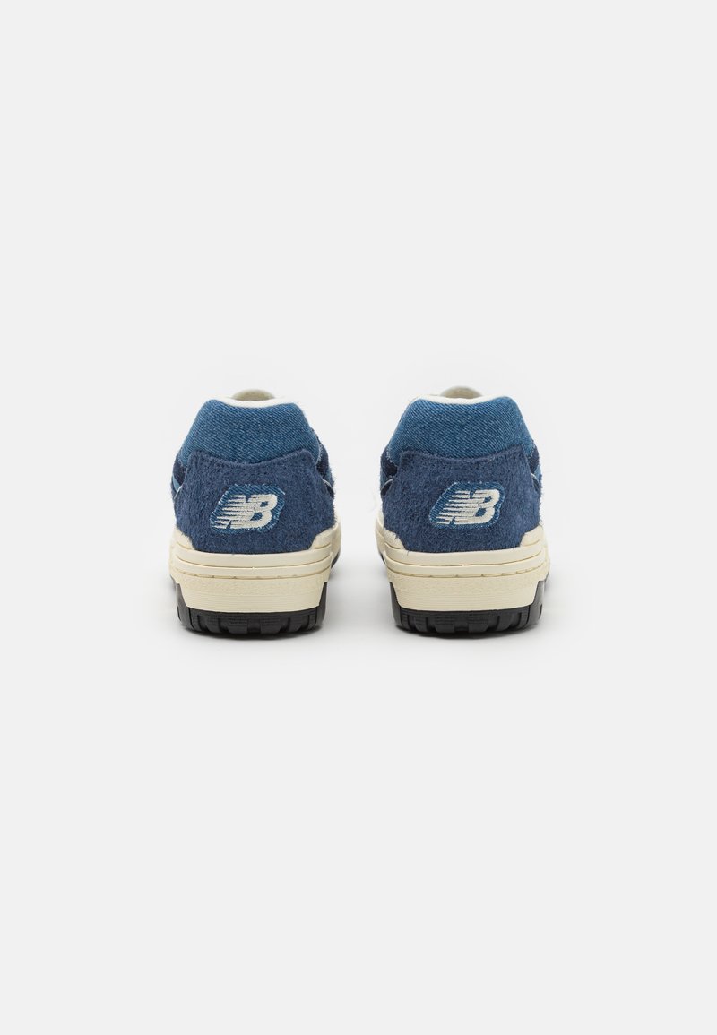 Baskets en daim bleu avec des accents blancs, dotées d'une semelle en caoutchouc noire et d'un branding visible sur le talon. Design à coupe basse avec une finition texturée.