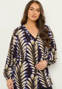 Blusa a maniche lunghe con scollatura a V di colore viola scuro, con motivo a foglie beige e blu, tessuto testurizzato e polsini elastici.