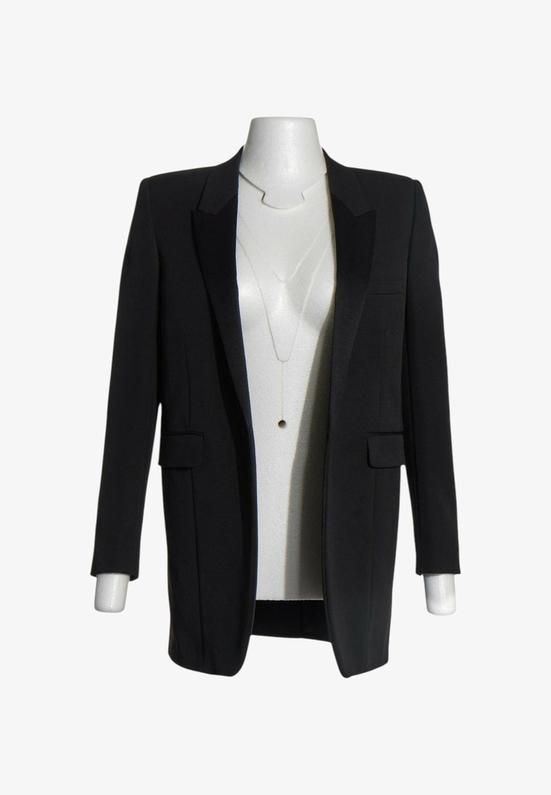 Blazer noir ajusté avec revers crantés et poches à rabats présenté sur un mannequin blanc sans tête sur fond blanc.
