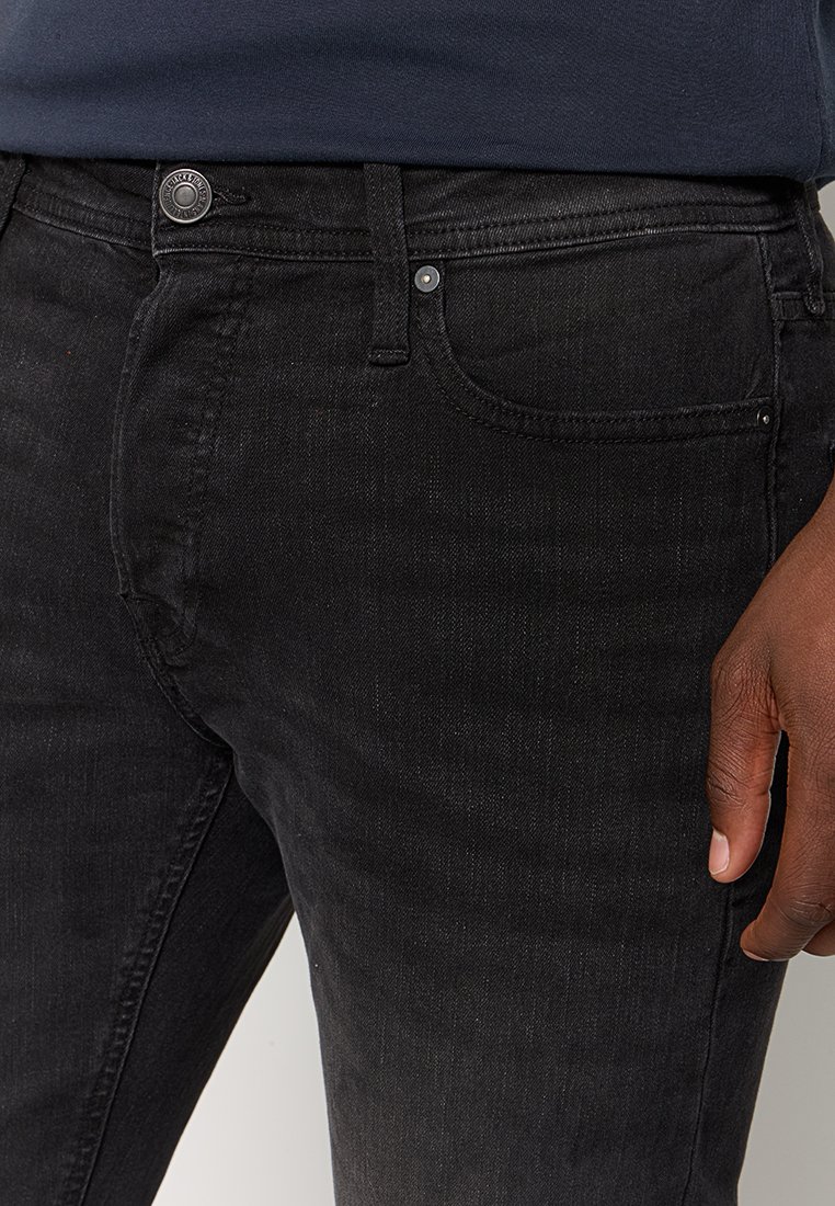 Schwarze Denim-Jeans mit glatter Textur, ausgestattet mit einer Fronttasche, metalldurchdringender Knopfverschluss und dezenten Nähdetails.