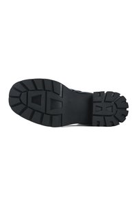 Suela de bota de goma negra con un patrón de relieve profundo, que presenta formas rectangulares y triangulares prominentes para mejorar el agarre y la tracción.