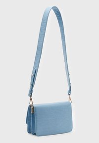 Niebieska torba na ramię z syntetycznej skóry imitującej wzór krokodyla, z długim regulowanym paskiem i złotymi dodatkami, z klapą zapinaną na zatrzask.