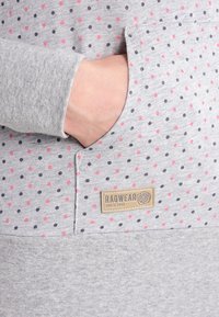 Grå sweatshirt med rosa och navyprickar, med en framficka och en märkespatch som säger "Ragwear Since 1997."