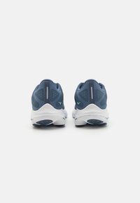 Scarpe sportive blu con tomaia in mesh, dettagli riflettenti e suola bianca imbottita. Presentano dettagli verdi sul tallone e suola con grip testurizzato.