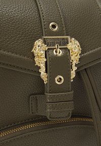 Olive green textured bag with gold hardware; features a decorative clasp and stitched accents; includes a zippered pocket.