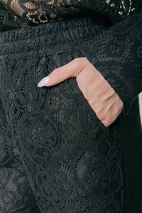 Fekete csipke nadrág bonyolult virágmintával, rugalmas derékrésszel és oldalzsebbel. Texturált anyag sima belső béléssel.