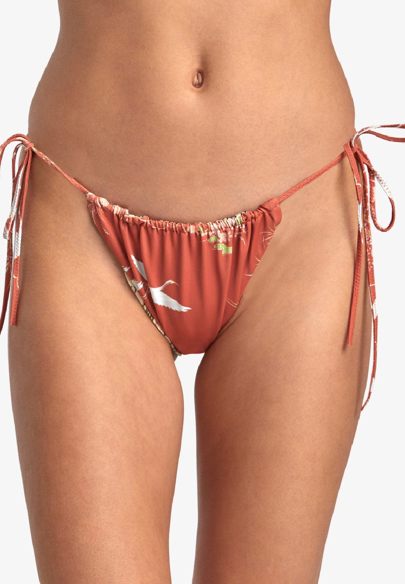Bas de bikini en terracotta avec motif floral, présentant des liens latéraux réglables et un tissu froncé pour une coupe ajustée. Texture douce.
