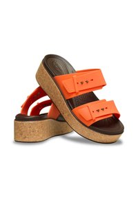 Sandales plateformes orange avec semelle en liège, dotées de deux larges sangles en caoutchouc et de petits clous décoratifs, conçues pour le confort et le soutien.