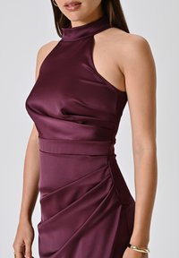 Burgunderfarbenes Satin-Halterkleid mit tailliertem Oberteil und drapierten Details. Glatte Textur, hoher Ausschnitt und asymmetrischer Schulterausschnitt.